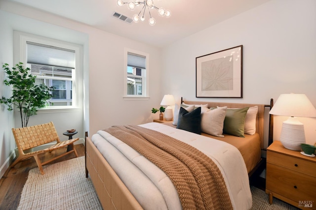 bedroom featuring an inviting chandelier and light hardwood / wood-style flooring