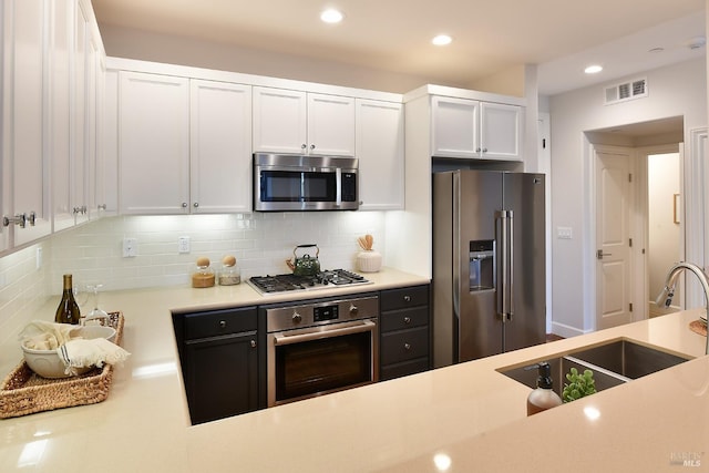 kitchen featuring stainless steel appliances, white cabinetry, sink, and backsplash