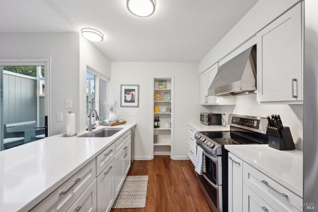 kitchen with wall chimney range hood, sink, stainless steel appliances, light stone counters, and white cabinets