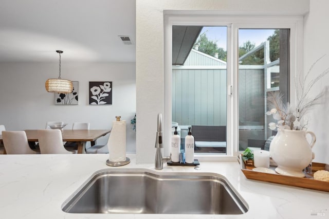 room details featuring hanging light fixtures, light stone countertops, and sink