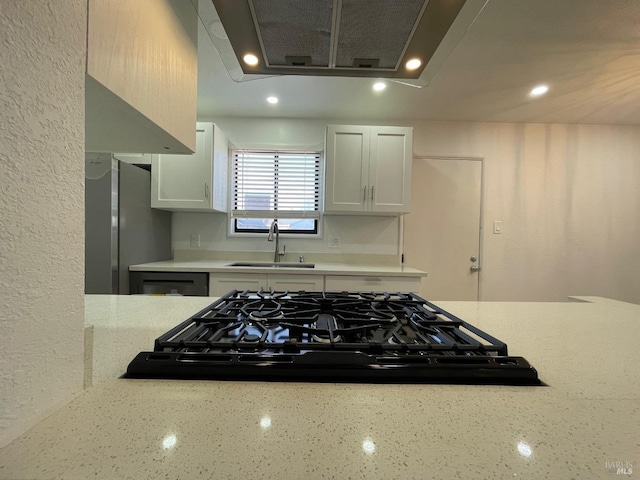 kitchen featuring sink, light stone countertops, white cabinets, and stainless steel refrigerator