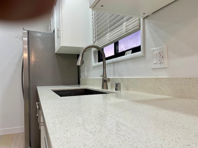 details featuring sink, white cabinetry, and light stone counters