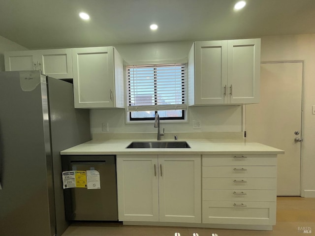 kitchen featuring dishwashing machine, white cabinetry, sink, and stainless steel refrigerator