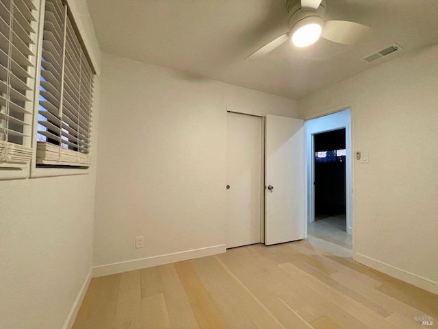 unfurnished bedroom featuring ceiling fan, light wood-type flooring, and a closet