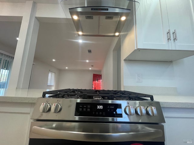 kitchen with white cabinetry, stainless steel range with gas cooktop, exhaust hood, and light stone counters