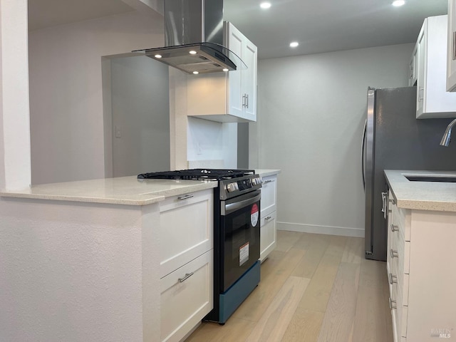 kitchen featuring light hardwood / wood-style flooring, white cabinets, range hood, stainless steel range with gas cooktop, and sink