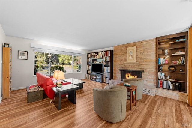 living room featuring built in features, a fireplace, and light hardwood / wood-style floors