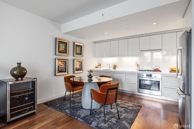 kitchen featuring dark hardwood / wood-style floors, appliances with stainless steel finishes, beverage cooler, and white cabinets