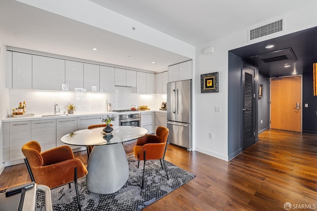 kitchen with sink, appliances with stainless steel finishes, tasteful backsplash, white cabinets, and dark hardwood / wood-style flooring