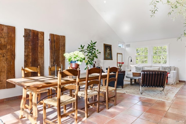 dining space with light tile patterned floors and high vaulted ceiling