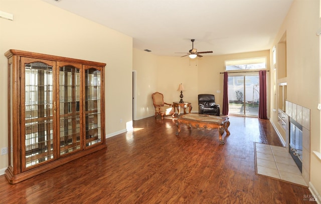 living room with hardwood / wood-style flooring, ceiling fan, and a tile fireplace