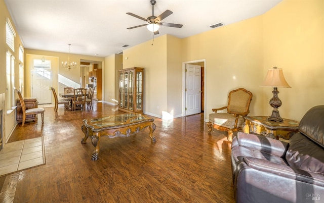 living room featuring ceiling fan with notable chandelier and dark wood-type flooring