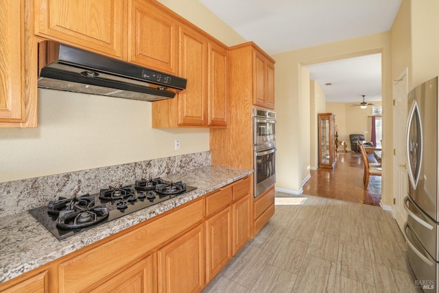 kitchen with ceiling fan, appliances with stainless steel finishes, and light stone counters