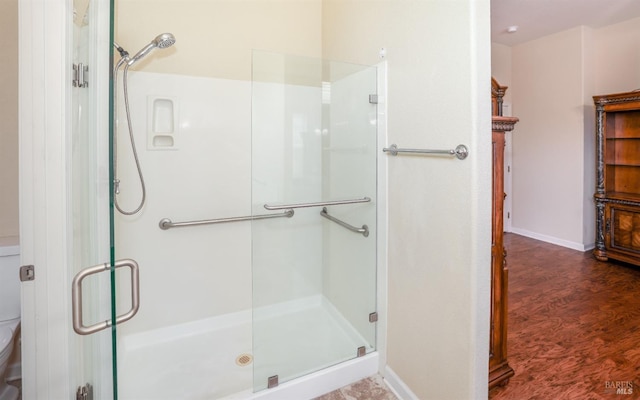 bathroom with a shower with door and hardwood / wood-style floors