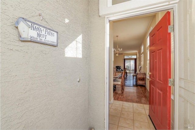 corridor featuring an inviting chandelier, light tile patterned floors, and a wealth of natural light