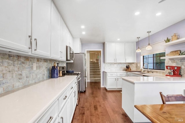 kitchen with pendant lighting, white cabinetry, sink, kitchen peninsula, and stainless steel appliances