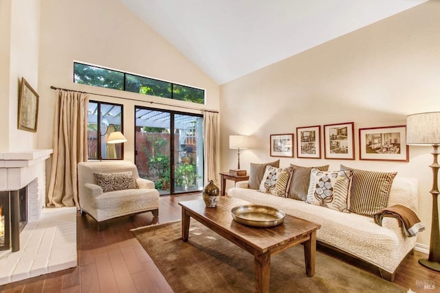 living room featuring hardwood / wood-style floors, high vaulted ceiling, and a brick fireplace