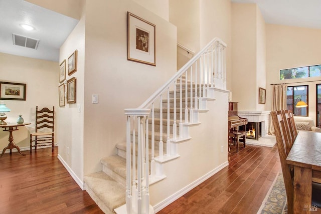 stairway with hardwood / wood-style floors and a brick fireplace