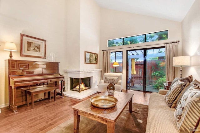 sitting room featuring a brick fireplace, wood-type flooring, and high vaulted ceiling