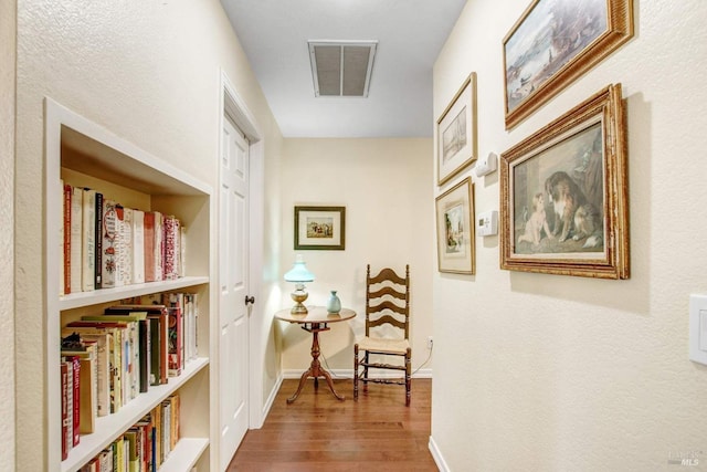 corridor with hardwood / wood-style flooring and built in features