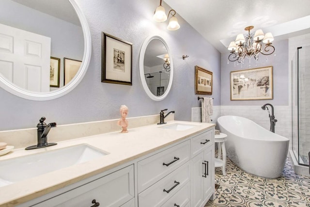 bathroom featuring a notable chandelier, vanity, tile patterned floors, and a tub