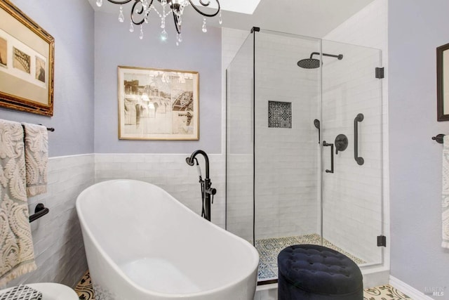 bathroom with shower with separate bathtub, a chandelier, and tile walls