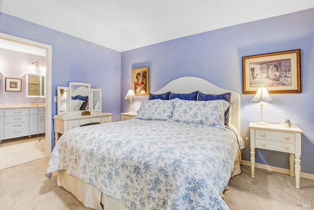 bedroom with ensuite bathroom and light carpet