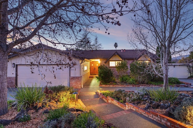 view of front of property with an attached garage, a tiled roof, and brick siding