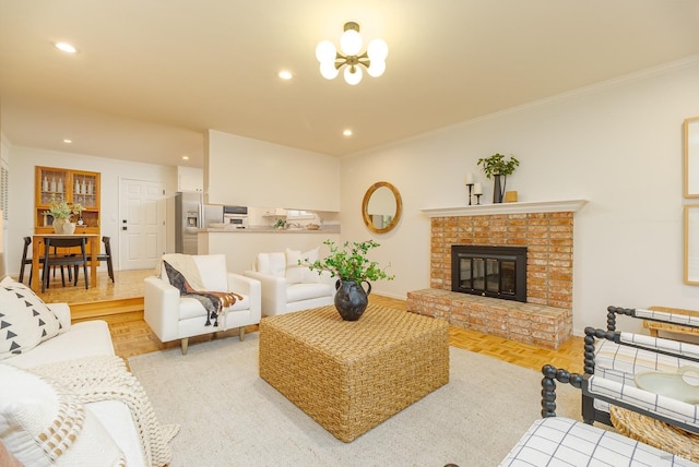 living room featuring recessed lighting, ornamental molding, a brick fireplace, a chandelier, and baseboards