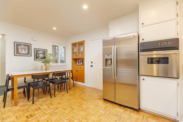 kitchen with recessed lighting, appliances with stainless steel finishes, white cabinets, and ornamental molding