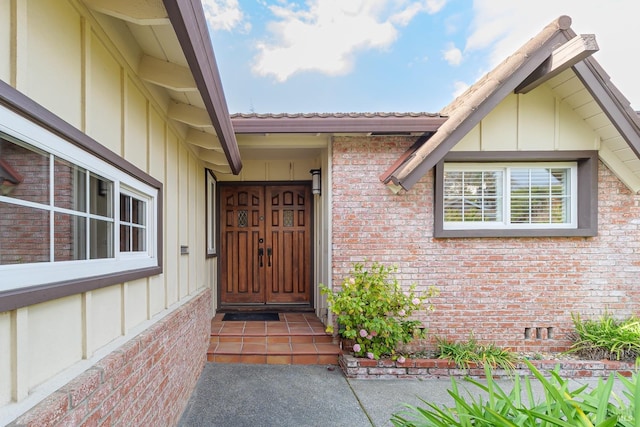 doorway to property with board and batten siding, crawl space, and brick siding