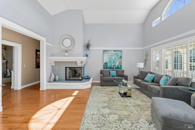 living room with lofted ceiling, a tiled fireplace, and hardwood / wood-style floors