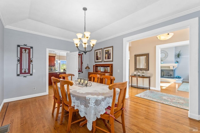 dining space with crown molding, a notable chandelier, light hardwood / wood-style floors, and a tray ceiling