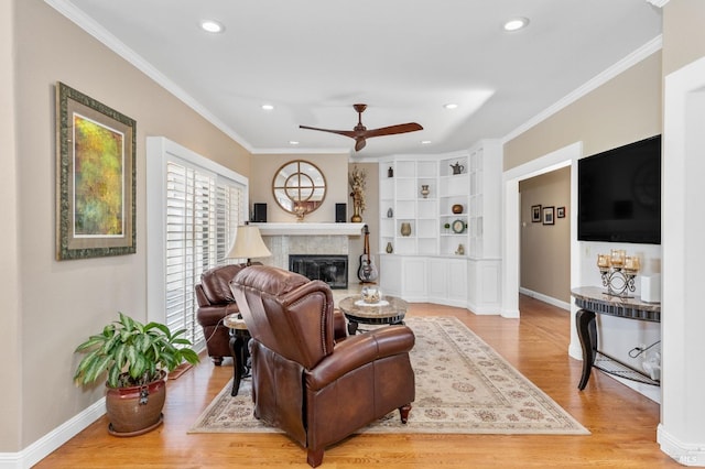 living room with crown molding, built in shelves, light hardwood / wood-style floors, and ceiling fan