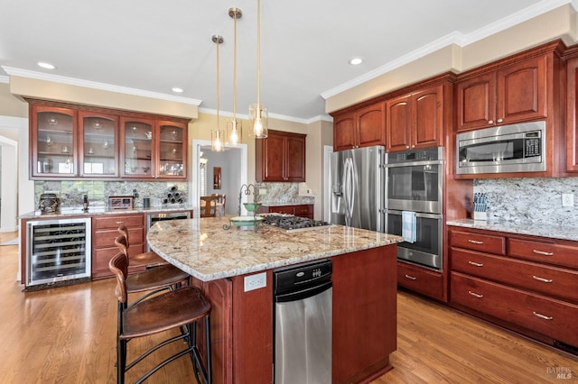 kitchen with appliances with stainless steel finishes, a kitchen island, decorative backsplash, decorative light fixtures, and beverage cooler