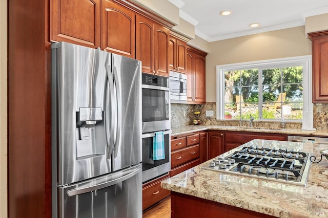 kitchen with ornamental molding, appliances with stainless steel finishes, sink, and light stone counters