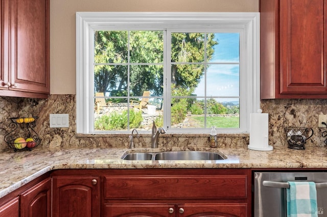 kitchen with light stone counters, dishwasher, sink, and backsplash