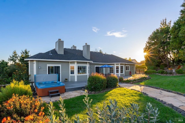 back of house with a yard, a hot tub, and a deck