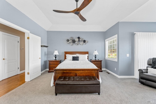 bedroom with light carpet, a raised ceiling, and ceiling fan