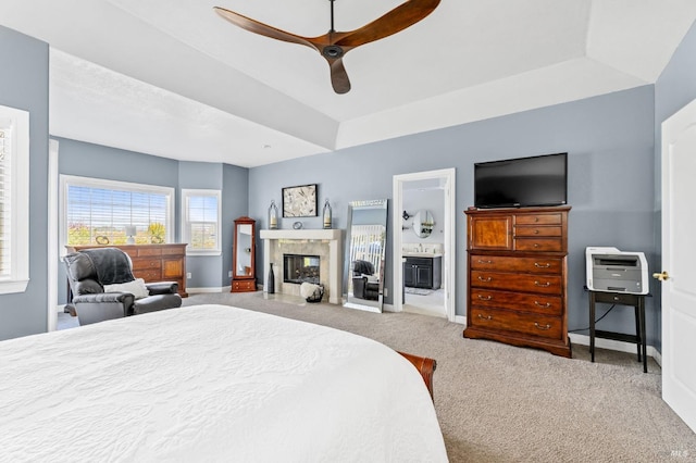 bedroom featuring ensuite bathroom, light carpet, ceiling fan, and a tray ceiling