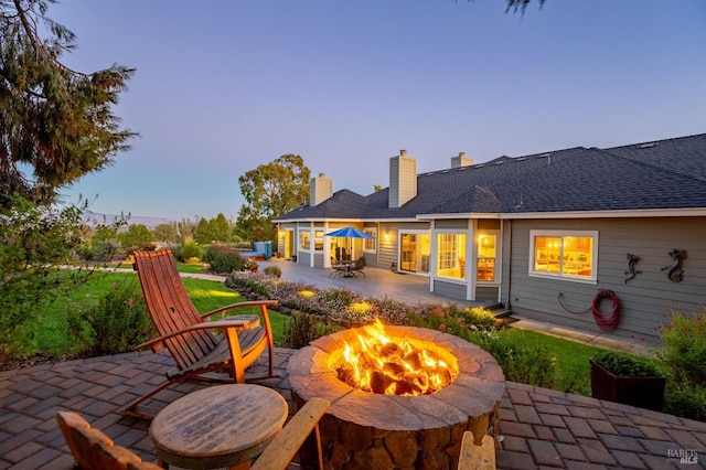 back house at dusk with a patio and an outdoor fire pit