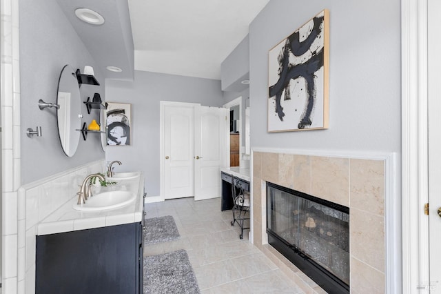 bathroom with tile patterned flooring, vanity, and a tile fireplace