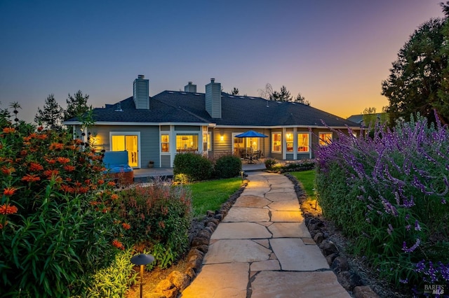 back house at dusk featuring a patio