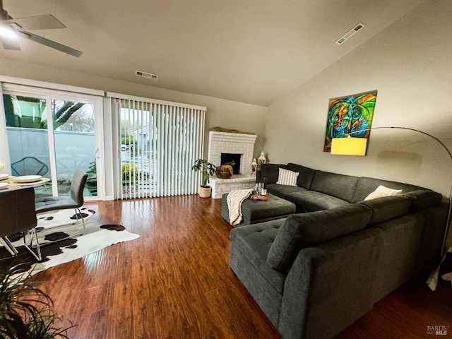 living area with lofted ceiling, a fireplace, visible vents, and wood finished floors