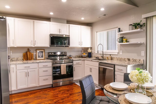 kitchen with visible vents, appliances with stainless steel finishes, dark wood-type flooring, white cabinetry, and a sink