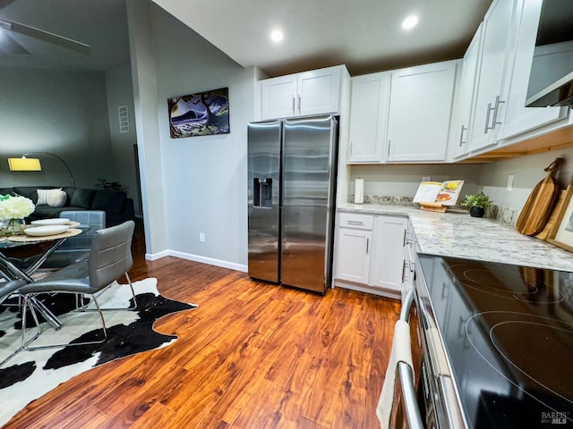 kitchen with white cabinetry, appliances with stainless steel finishes, light stone counters, and wood finished floors