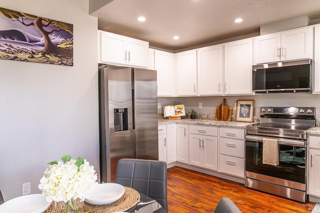 kitchen featuring light stone counters, recessed lighting, appliances with stainless steel finishes, dark wood-type flooring, and white cabinets