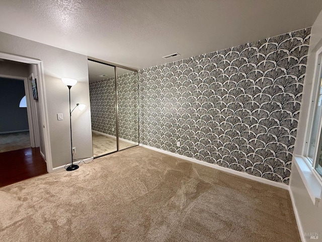 unfurnished bedroom featuring wallpapered walls, visible vents, and carpet flooring