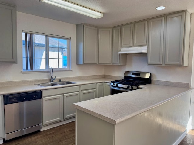 kitchen featuring sink, gray cabinetry, appliances with stainless steel finishes, dark hardwood / wood-style flooring, and kitchen peninsula