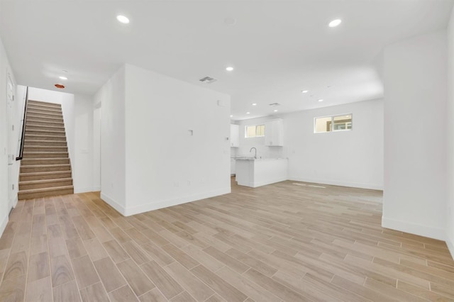 unfurnished living room featuring sink and light hardwood / wood-style floors